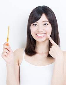 Woman pointing to her bright white smile after teeth whitening
