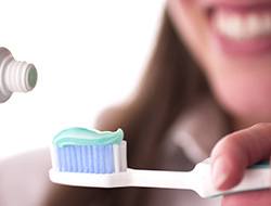 Smiling woman putting toothpaste on toothbrush