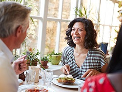 Woman smiling while eating at restaurant with friends