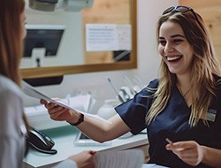 Smiling dental receptionist helping patient with paperwork